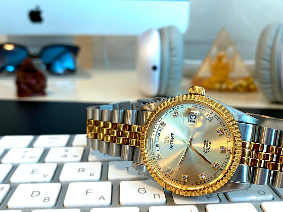 A gold watch on top of a keyboard represents timing bullion purchases